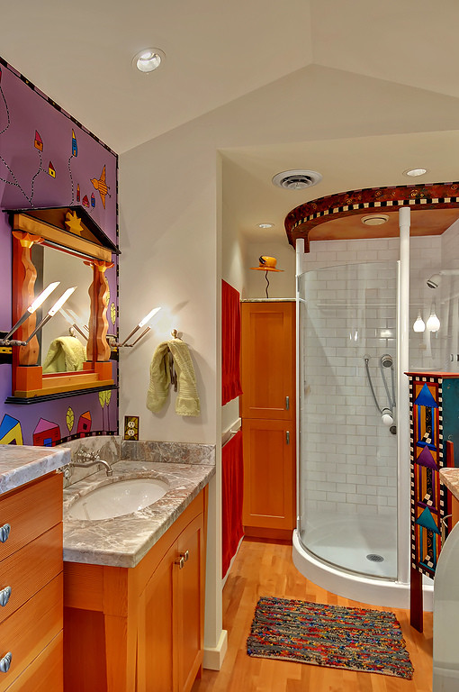 Cette image montre une salle de bain bohème en bois brun avec un placard à porte shaker, une douche d'angle, un carrelage blanc, un mur violet et parquet clair.