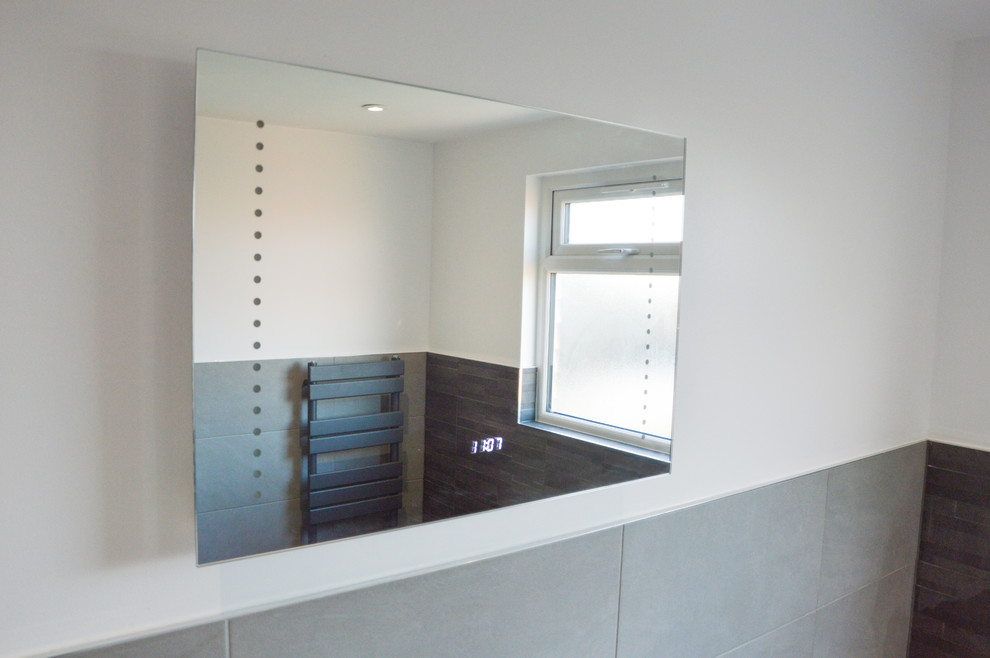 This is an example of a large contemporary family bathroom in London with a freestanding bath, a walk-in shower, a one-piece toilet, grey tiles, stone slabs, grey walls, a wall-mounted sink, grey floors and a sliding door.