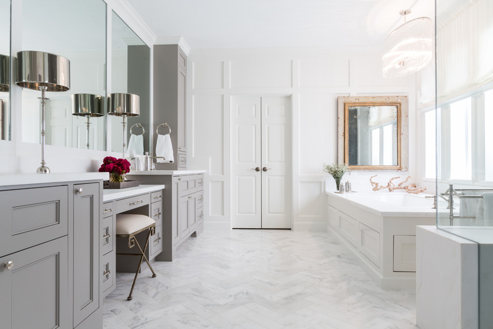 Cette photo montre une salle de bain principale chic avec un placard avec porte à panneau encastré, des portes de placard grises, une baignoire encastrée, un mur blanc et un sol blanc.