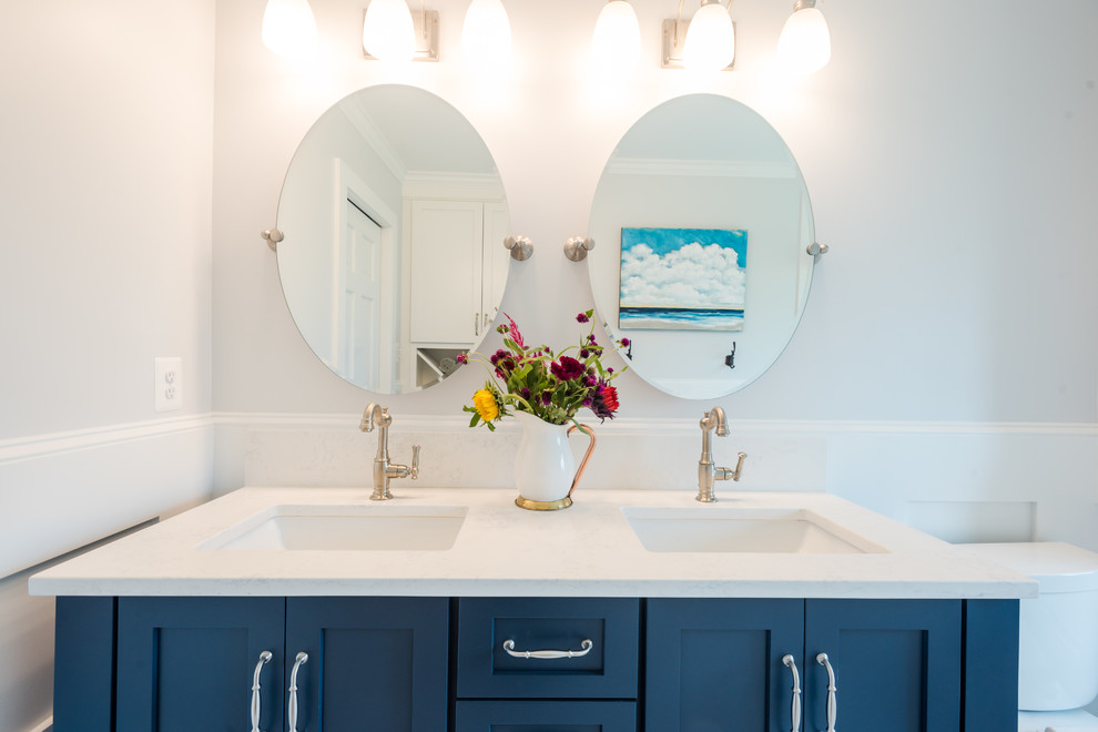 Cette image montre une petite salle d'eau traditionnelle avec un placard à porte shaker, des portes de placard bleues, un combiné douche/baignoire, un mur gris, un lavabo encastré, un plan de toilette en quartz modifié, un sol gris et un plan de toilette blanc.