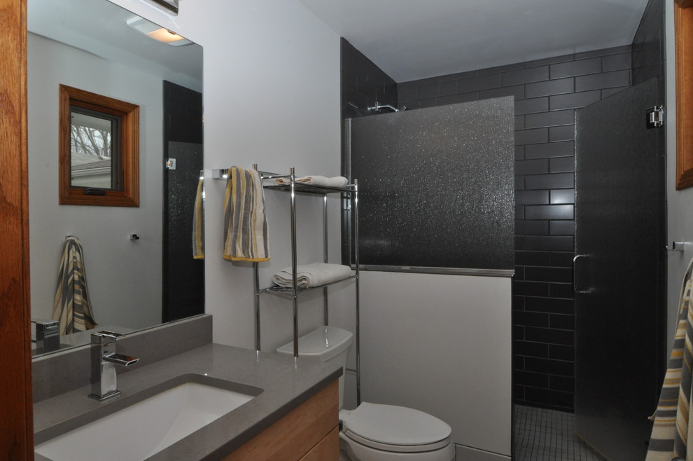 Cette image montre une petite salle d'eau minimaliste en bois clair avec un placard à porte plane, une douche d'angle, WC séparés, des plaques de verre, un mur blanc, un lavabo encastré et un plan de toilette en quartz.