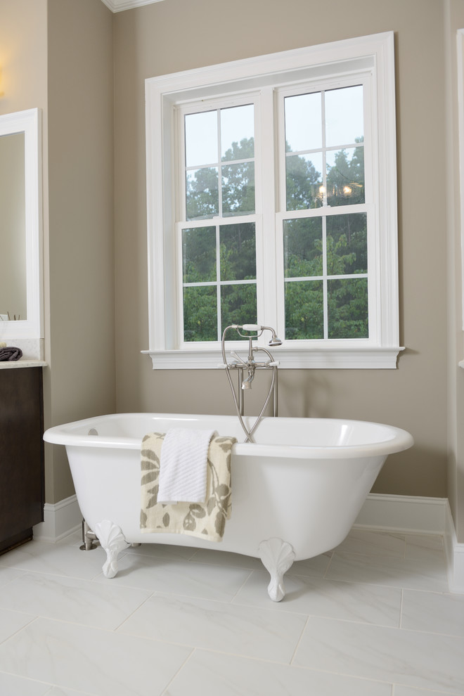 Diseño de cuarto de baño tradicional con puertas de armario de madera en tonos medios, bañera con patas, baldosas y/o azulejos blancos y paredes beige