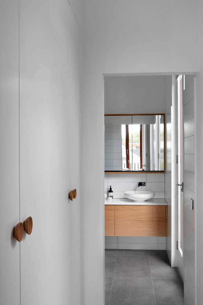Свежая идея для дизайна: большая ванная комната в современном стиле с плоскими фасадами, фасадами цвета дерева среднего тона, отдельно стоящей ванной, душевой комнатой, унитазом-моноблоком, синей плиткой, плиткой кабанчик, белыми стенами, душевой кабиной, настольной раковиной, серым полом, открытым душем и белой столешницей - отличное фото интерьера