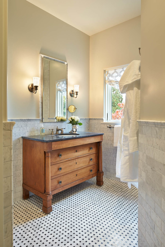 Cette image montre une salle de bain traditionnelle en bois brun avec un lavabo encastré, un carrelage blanc, un carrelage métro, un mur beige, du carrelage bicolore et un placard à porte plane.