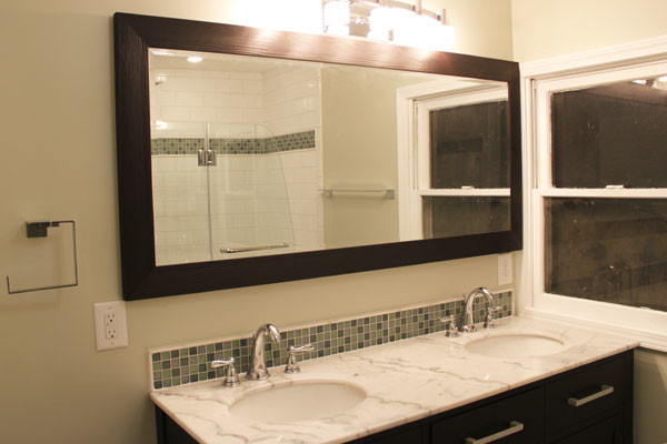 Bild på ett vintage badrum, med ett undermonterad handfat, luckor med infälld panel, svarta skåp, marmorbänkskiva och en dusch/badkar-kombination