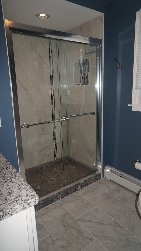 Photo of a medium sized classic ensuite bathroom in Philadelphia with flat-panel cabinets, white cabinets, an alcove bath, an alcove shower, a two-piece toilet, grey tiles, porcelain tiles, blue walls, porcelain flooring, a submerged sink and granite worktops.
