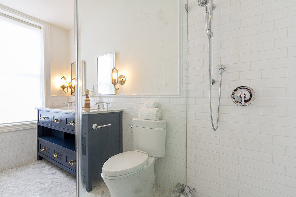 Photo of an expansive classic ensuite bathroom in New York with shaker cabinets, blue cabinets, a two-piece toilet, white tiles, porcelain tiles, white walls, marble flooring, a submerged sink, marble worktops, white floors and a hinged door.