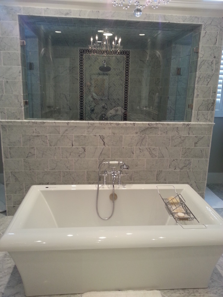 Klassisk inredning av ett stort en-suite badrum, med marmorbänkskiva, ett fristående badkar, en dubbeldusch, grå kakel, stenkakel, grå väggar och marmorgolv
