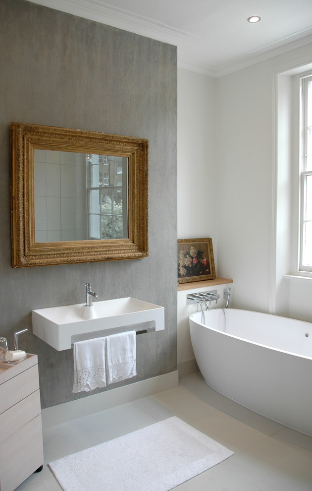 Imagen de cuarto de baño principal moderno de tamaño medio con bañera exenta, baldosas y/o azulejos grises, paredes grises y suelo de baldosas de porcelana