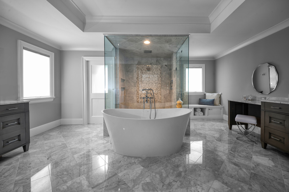 На фото: большая главная ванная комната в стиле неоклассика (современная классика) с коричневыми фасадами, отдельно стоящей ванной, мраморным полом, мраморной столешницей и серым полом