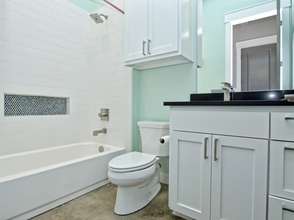 Cette image montre une salle d'eau traditionnelle de taille moyenne avec un placard à porte shaker, des portes de placard blanches, une baignoire en alcôve, un combiné douche/baignoire, WC séparés, un carrelage blanc, un carrelage métro, un mur vert, sol en béton ciré, un lavabo encastré, un plan de toilette en quartz modifié, un sol marron, une cabine de douche avec un rideau et un plan de toilette noir.