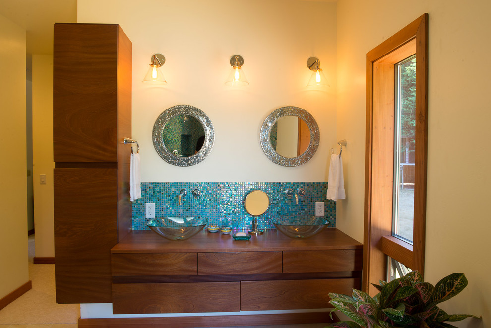 Example of a mid-sized eclectic master blue tile and glass tile porcelain tile corner shower design in Other with flat-panel cabinets, medium tone wood cabinets, a two-piece toilet, beige walls, a vessel sink and wood countertops
