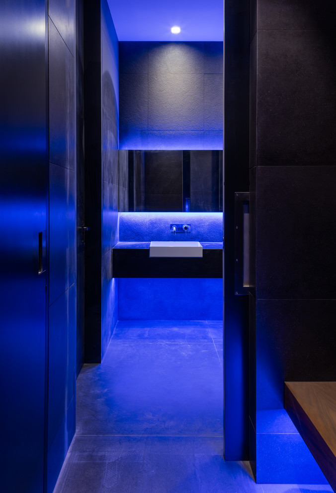 На фото: ванная комната среднего размера в современном стиле с черной плиткой, керамогранитной плиткой, полом из керамогранита, монолитной раковиной и черным полом с