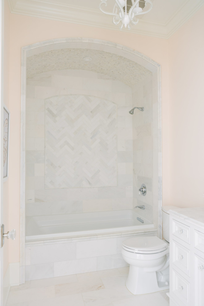 Стильный дизайн: ванная комната в стиле неоклассика (современная классика) с фасадами островного типа, белыми фасадами, ванной в нише, душем над ванной, раздельным унитазом, розовой плиткой, синими стенами, полом из керамогранита, врезной раковиной, мраморной столешницей, серым полом, открытым душем и белой столешницей - последний тренд