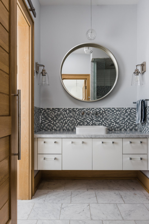 Gray Glass Backsplash Behind Bathroom Sink and White Cabinet