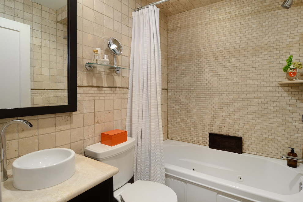 Идея дизайна: ванная комната в современном стиле с настольной раковиной, плоскими фасадами, темными деревянными фасадами, мраморной столешницей, ванной в нише, душем над ванной, раздельным унитазом, бежевой плиткой и каменной плиткой