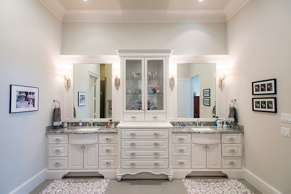 Modelo de cuarto de baño principal campestre grande con armarios con paneles empotrados, puertas de armario blancas, paredes blancas, lavabo tipo consola, encimera de granito, suelo gris y encimeras grises