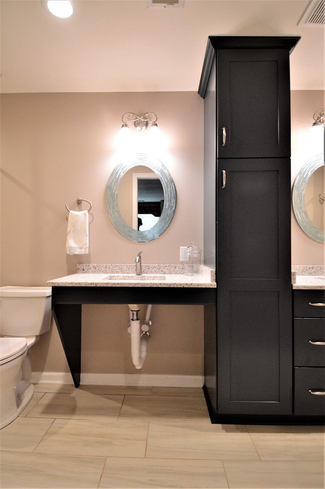 This is an example of a large traditional ensuite bathroom in Milwaukee with recessed-panel cabinets, black cabinets, an alcove bath, an alcove shower, a two-piece toilet, grey tiles, stone tiles, beige walls, laminate floors, a wall-mounted sink, laminate worktops, beige floors and an open shower.