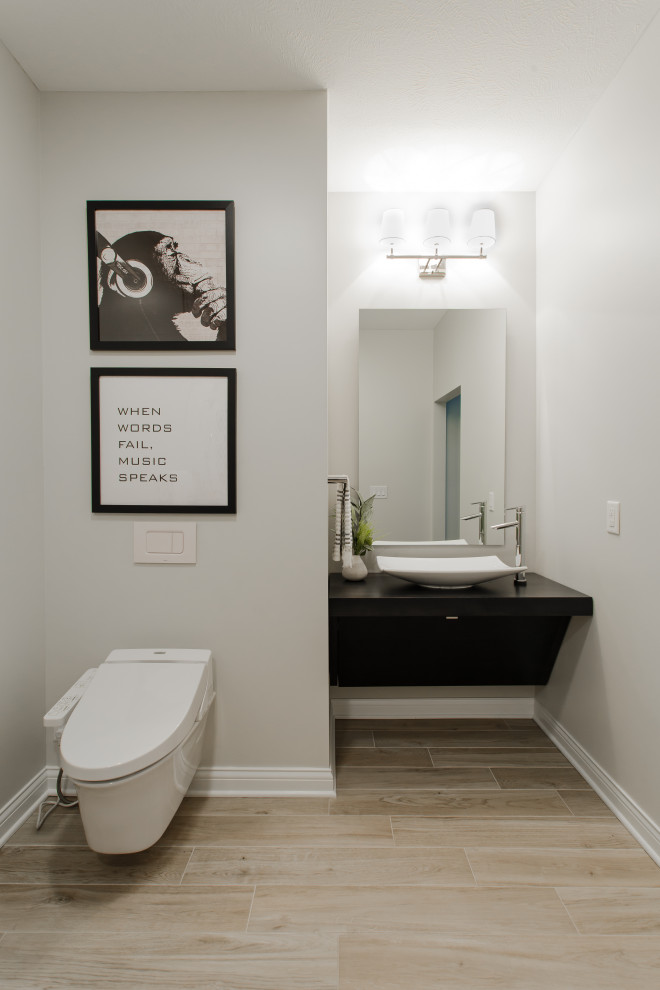 This is an example of a medium sized traditional ensuite bathroom in Cleveland with flat-panel cabinets, black cabinets, a built-in shower, a wall mounted toilet, white tiles, marble tiles, beige walls, porcelain flooring, a vessel sink, wooden worktops, beige floors, an open shower, black worktops, a single sink and a floating vanity unit.
