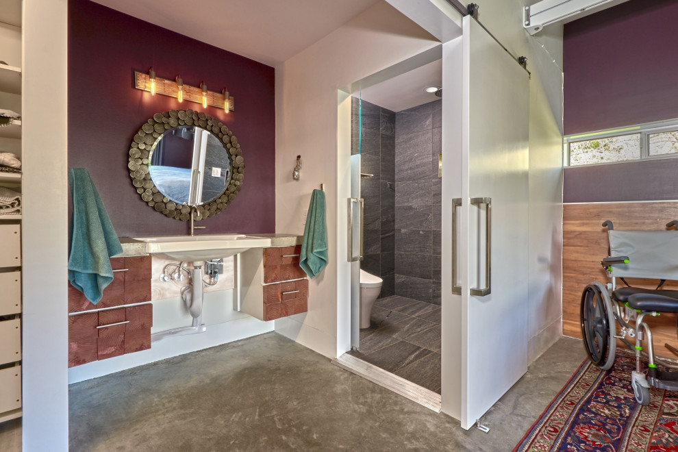 На фото: главная ванная комната среднего размера в стиле фьюжн с фасадами цвета дерева среднего тона, душем без бортиков, унитазом-моноблоком, фиолетовыми стенами, бетонным полом, подвесной раковиной, столешницей из бетона, серым полом, душем с раздвижными дверями, серой столешницей, тумбой под одну раковину, подвесной тумбой, балками на потолке и панелями на части стены