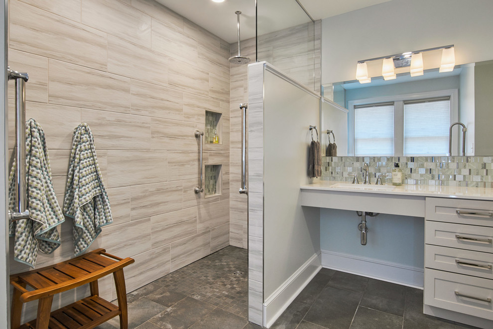 Photo of an expansive modern ensuite bathroom in St Louis with recessed-panel cabinets, white cabinets, a walk-in shower, a one-piece toilet, beige tiles, grey walls, slate flooring, a built-in sink, solid surface worktops, grey floors, an open shower and white worktops.