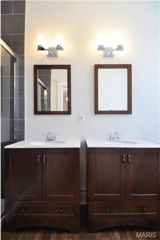 Diseño de cuarto de baño principal tradicional renovado de tamaño medio con lavabo con pedestal, armarios estilo shaker, puertas de armario de madera oscura, encimera de granito y suelo de madera en tonos medios