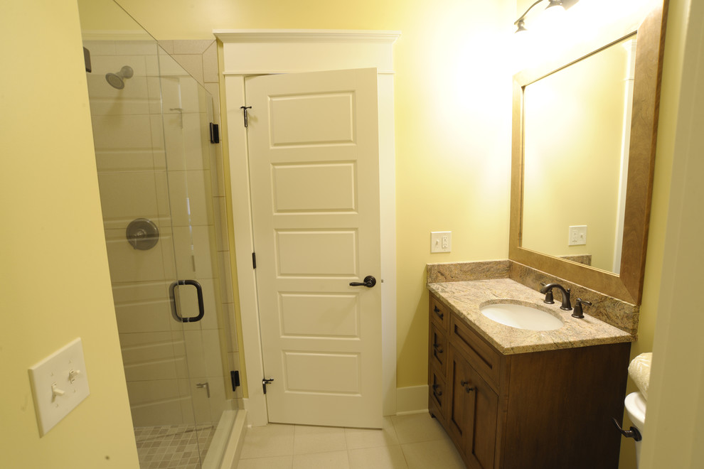 Inspiration for a classic family bathroom in Columbus with shaker cabinets, medium wood cabinets, an alcove shower, yellow walls, a submerged sink, white floors, a hinged door, a single sink and a built in vanity unit.