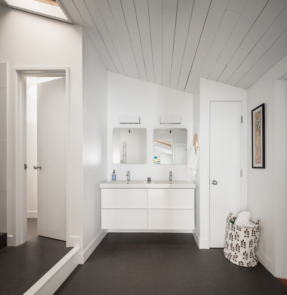 Diseño de cuarto de baño infantil, doble y flotante vintage con armarios con paneles lisos, puertas de armario blancas, paredes blancas, lavabo integrado, suelo gris, encimeras blancas y espejo con luz