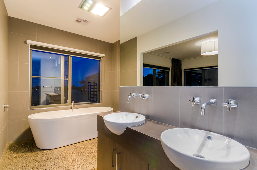 Идея дизайна: большая главная ванная комната в современном стиле с накладной раковиной, фасадами цвета дерева среднего тона, отдельно стоящей ванной, открытым душем, унитазом-моноблоком, серой плиткой, керамической плиткой, серыми стенами и бетонным полом