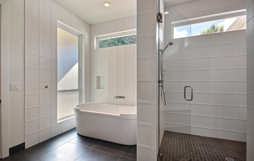 На фото: огромная главная ванная комната в стиле модернизм с плоскими фасадами, светлыми деревянными фасадами, отдельно стоящей ванной, двойным душем, биде, белой плиткой, керамической плиткой, белыми стенами, полом из цементной плитки, настольной раковиной, столешницей из искусственного кварца, серым полом, душем с распашными дверями и бежевой столешницей