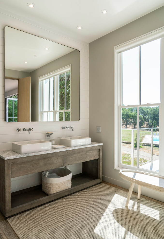 Diseño de cuarto de baño campestre con armarios abiertos, puertas de armario de madera en tonos medios, paredes blancas, lavabo sobreencimera y encimeras blancas