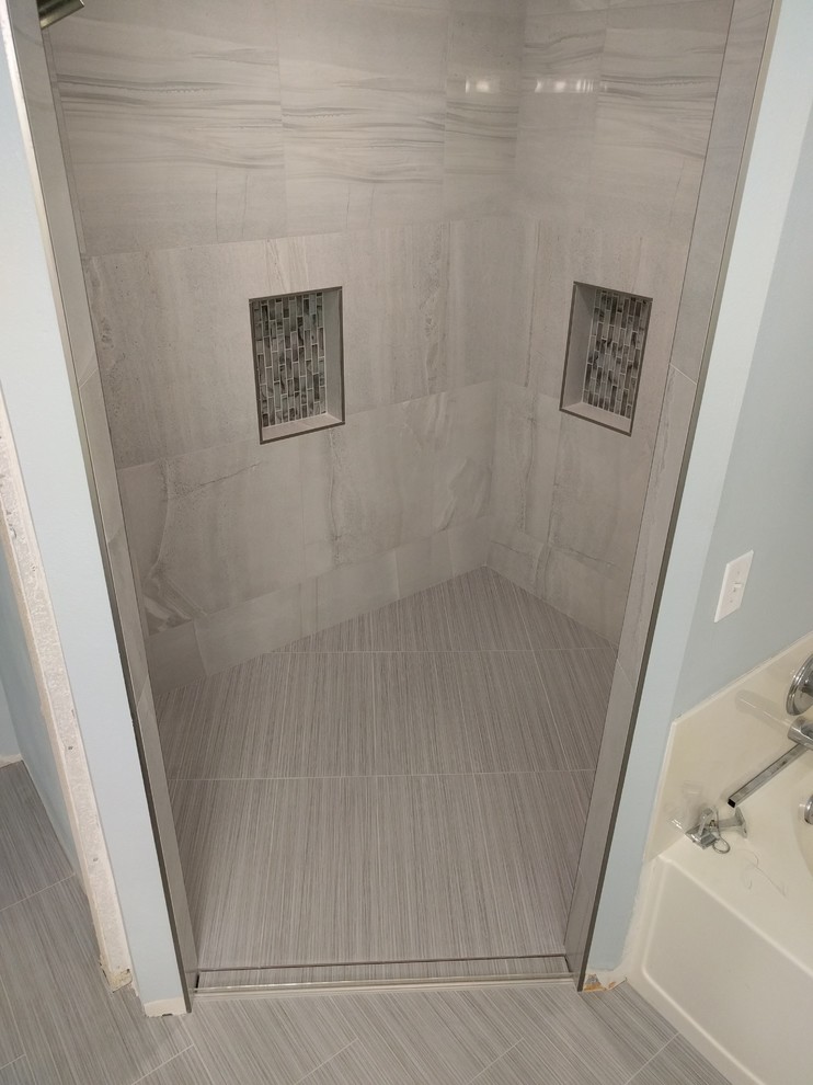 Bild på ett mellanstort funkis en-suite badrum, med skåp i shakerstil, skåp i mörkt trä, en kantlös dusch, vit kakel, porslinskakel, blå väggar, klinkergolv i porslin, ett avlångt handfat och kaklad bänkskiva