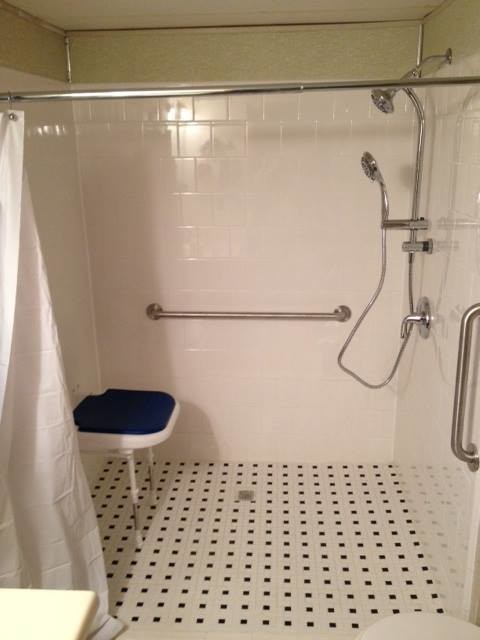 Bild på ett lantligt badrum, med en kantlös dusch, en toalettstol med hel cisternkåpa, gröna väggar, klinkergolv i keramik, ett väggmonterat handfat, vitt golv och dusch med duschdraperi