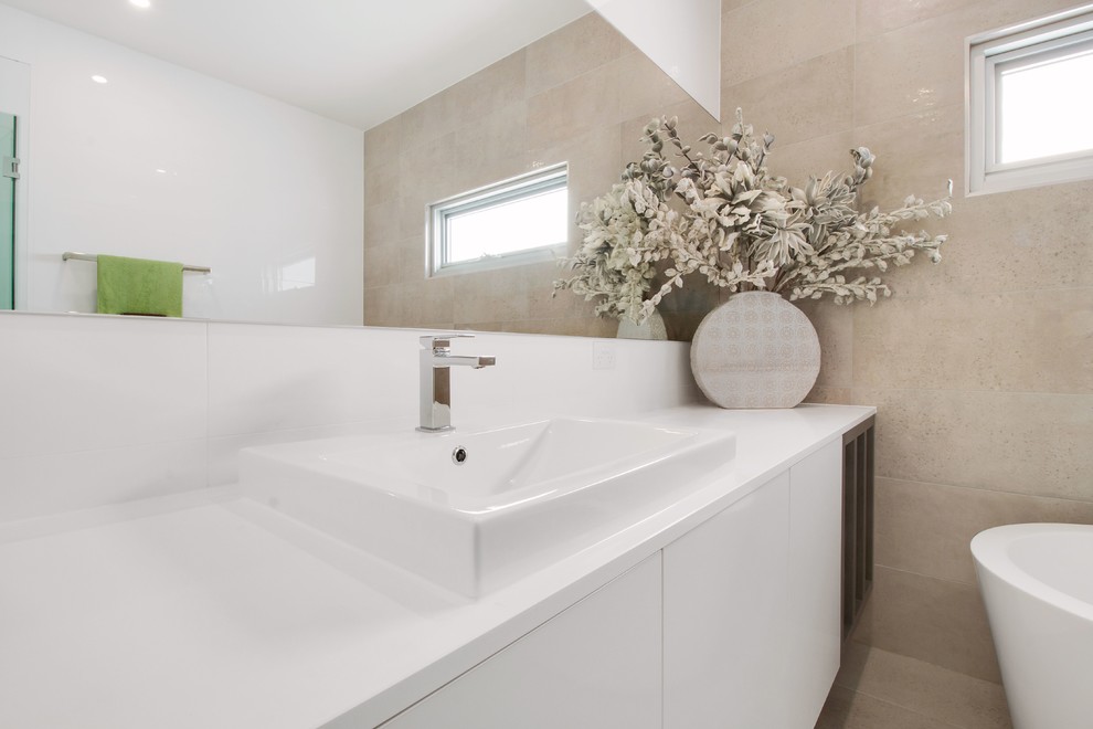 Immagine di una grande stanza da bagno con doccia minimal con vasca freestanding, WC monopezzo, piastrelle beige, piastrelle in ceramica, pareti beige e pavimento con piastrelle in ceramica