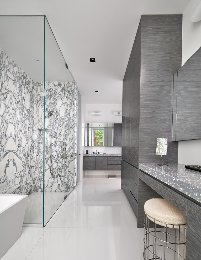 Inspiration för ett funkis grå grått badrum, med bänkskiva i betong, släta luckor, grå skåp, ett fristående badkar, en kantlös dusch, svart och vit kakel, stenhäll, vita väggar, vitt golv och dusch med gångjärnsdörr