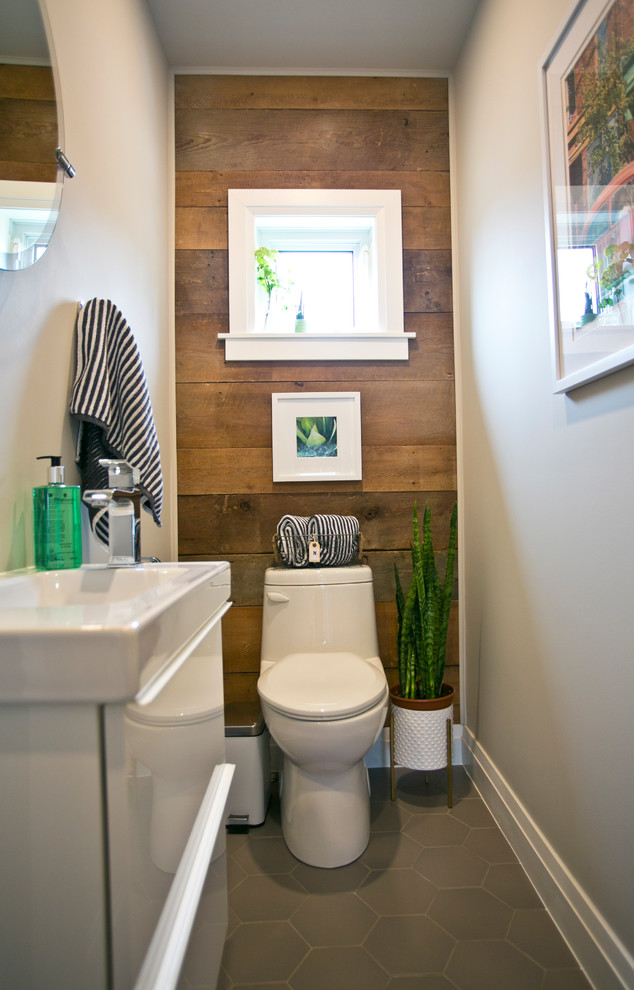 Cette photo montre une petite salle de bain rétro avec un placard à porte plane, des portes de placard blanches, WC à poser, un mur gris, un sol en carrelage de céramique, un plan de toilette en surface solide et un sol gris.