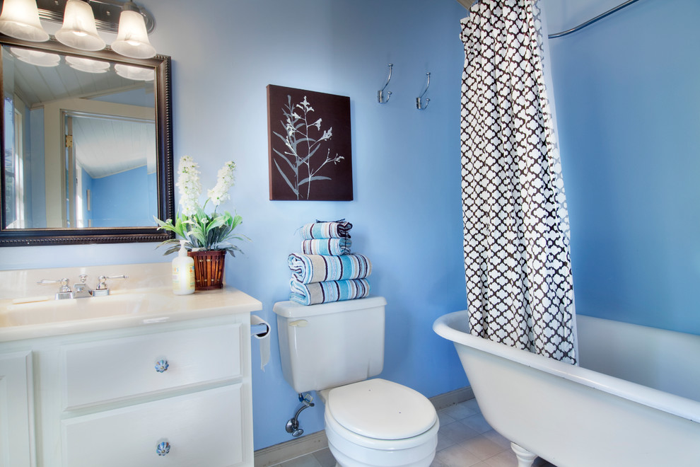 Cette photo montre une salle de bain moderne de taille moyenne pour enfant avec un placard avec porte à panneau surélevé, des portes de placard blanches, un plan de toilette en stratifié, un lavabo intégré, une baignoire sur pieds, un carrelage beige, un mur bleu et un sol en linoléum.