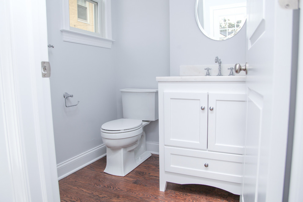 Exemple d'une petite salle d'eau chic avec un placard à porte shaker, des portes de placard blanches, WC séparés, un mur gris, parquet foncé et un plan de toilette en marbre.