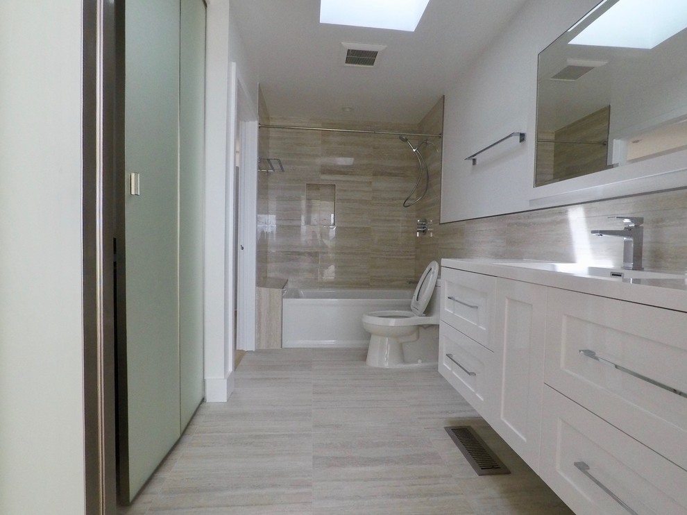 Пример оригинального дизайна: главная ванная комната среднего размера в современном стиле с фасадами в стиле шейкер, белыми фасадами, ванной в нише, душем над ванной, унитазом-моноблоком, бежевой плиткой, плиткой из известняка, белыми стенами, шторкой для ванной и белой столешницей