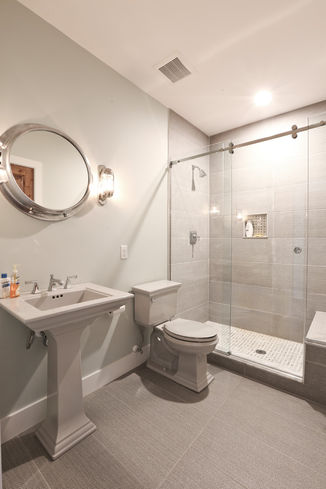 Пример оригинального дизайна: ванная комната среднего размера в стиле кантри с душем в нише, унитазом-моноблоком, серой плиткой, керамогранитной плиткой, серыми стенами, душевой кабиной, раковиной с пьедесталом, серым полом, душем с раздвижными дверями, полом из ламината и столешницей из искусственного камня