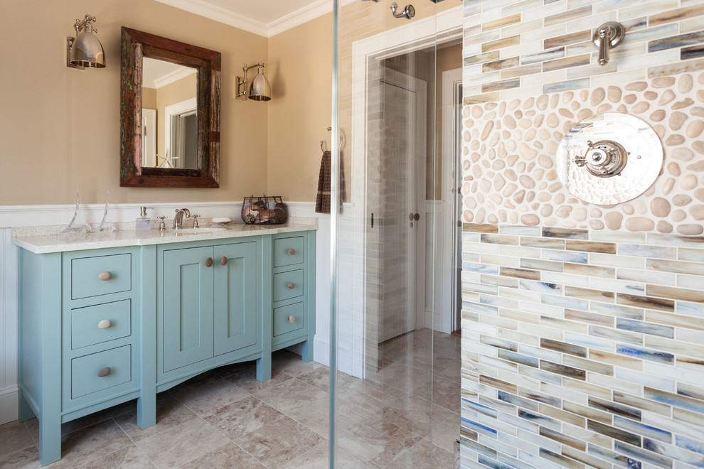 Esempio di una stanza da bagno chic di medie dimensioni con lavabo sottopiano, ante a filo, ante blu, top in vetro riciclato, doccia ad angolo, piastrelle beige, piastrelle in pietra e pareti beige