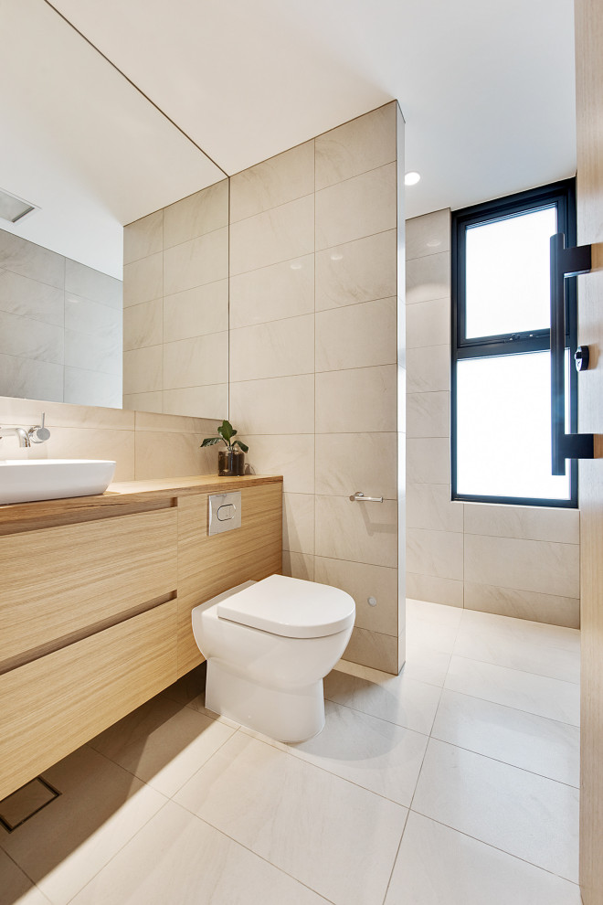Inspiration for a large contemporary shower room bathroom in Adelaide with flat-panel cabinets, beige cabinets, a wall mounted toilet, beige tiles, porcelain tiles, beige walls, porcelain flooring, a vessel sink, wooden worktops, beige floors, beige worktops, a single sink and a built in vanity unit.