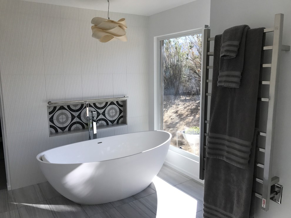 Ejemplo de cuarto de baño principal actual de tamaño medio con bañera exenta, paredes beige y suelo gris