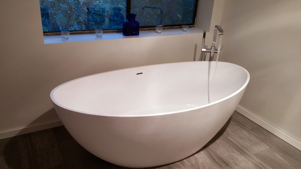 Idée de décoration pour une salle de bain principale design de taille moyenne avec une baignoire indépendante, un mur blanc et un sol beige.