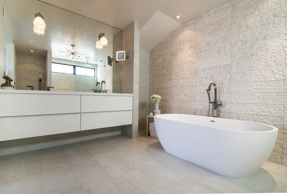 Réalisation d'une grande salle de bain principale design avec une baignoire indépendante, un placard à porte plane, des portes de placard blanches, un mur beige, un plan de toilette en surface solide, un sol beige et un plan de toilette blanc.