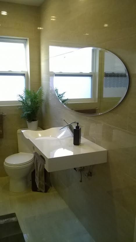 Immagine di una stanza da bagno padronale contemporanea di medie dimensioni con lavabo sospeso, WC monopezzo, pareti beige, top in superficie solida, pavimento grigio e top bianco