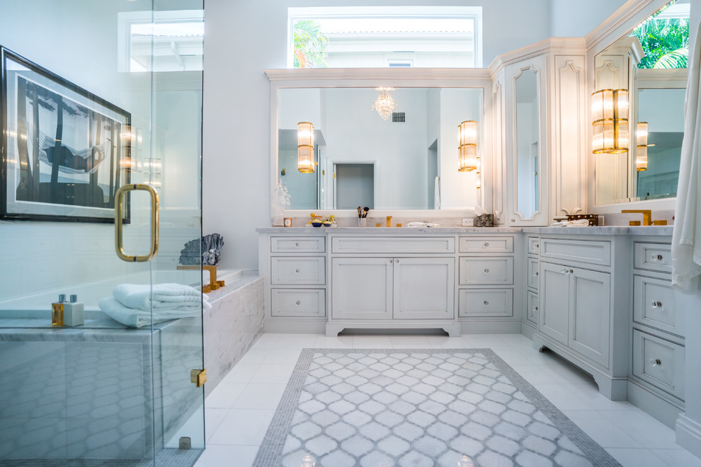 Cette photo montre une salle de bain principale tendance avec un placard avec porte à panneau encastré, des portes de placard grises, une baignoire posée, un espace douche bain, un carrelage gris, un carrelage blanc, un mur gris, un sol en marbre, un lavabo encastré et un plan de toilette en marbre.
