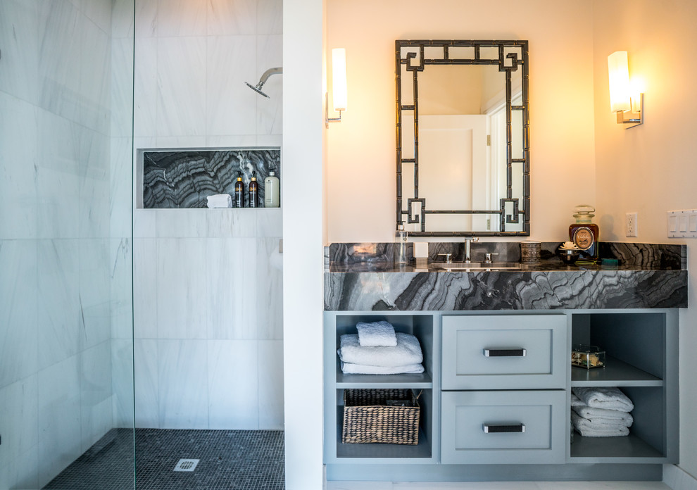 Foto på ett mellanstort funkis badrum med dusch, med öppna hyllor, blå skåp, en öppen dusch, grå kakel, vit kakel, beige väggar, ett nedsänkt handfat och marmorbänkskiva