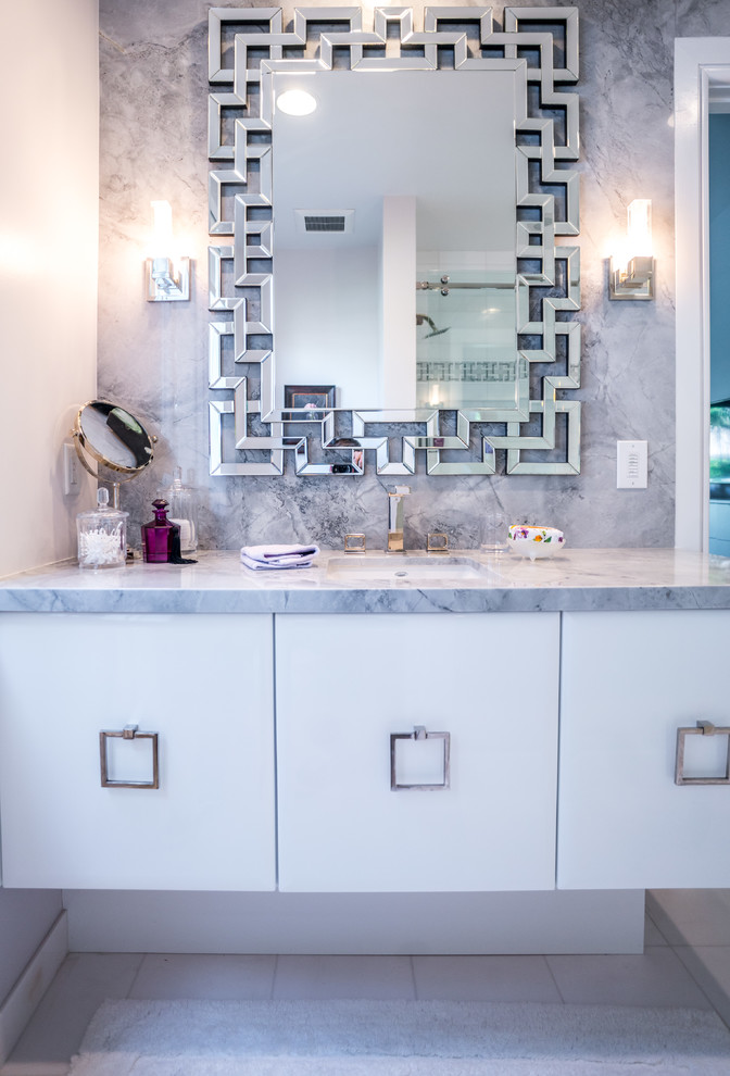 Modelo de cuarto de baño contemporáneo de tamaño medio con armarios con paneles lisos, puertas de armario blancas, paredes grises, aseo y ducha, lavabo bajoencimera y encimera de mármol
