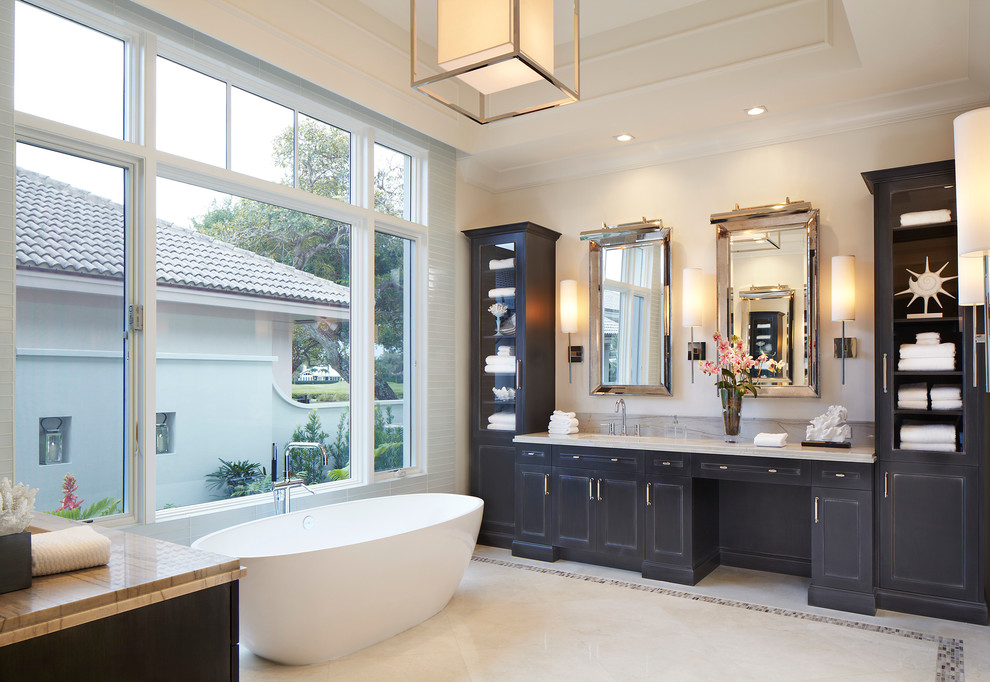 Imagen de cuarto de baño tropical con armarios con paneles con relieve, puertas de armario negras y bañera exenta
